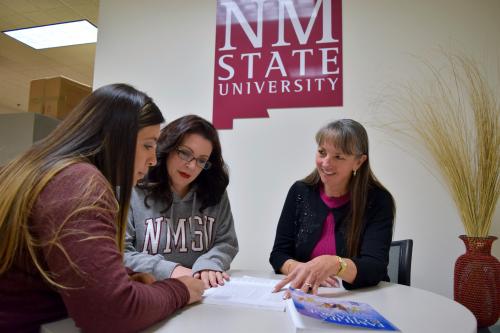 Two women explaining a book to a student